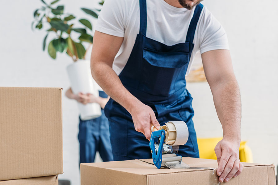 vue de près d'un employé scotchant un carton